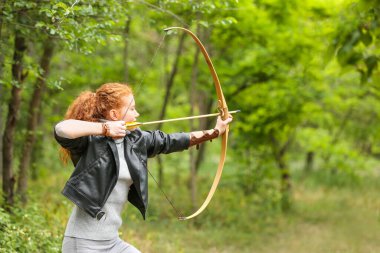 Dışarıda okçuluk yapan genç bir bayan.
