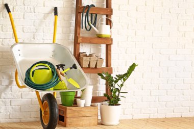 Tuğla duvarın yanında bahçe malzemeleri var.