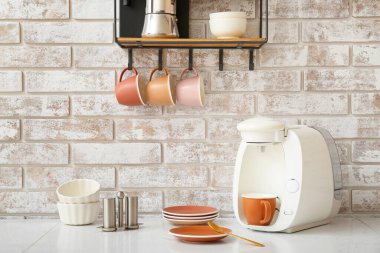 Shelf with cups and coffee machine on table in kitchen clipart