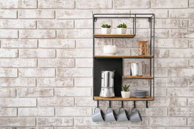 Tuğla duvarda mutfak gereçleri olan raflar.