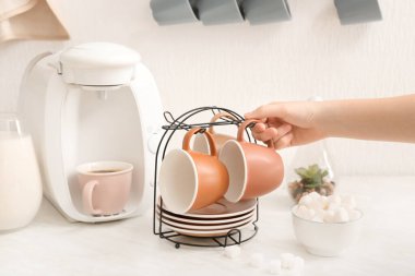 Mutfakta fincan ve tabak tutacağı olan bir kadın.