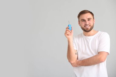 Gri arka planda araba anahtarı olan genç bir adam.