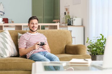 Evde video oyunu oynayan yakışıklı genç adam.