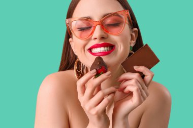 Çilekli ve çikolata rengi arka planda seksi bir genç kadın.