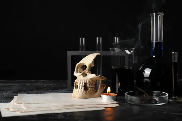 Potions, human skull and candle on alchemist\'s table