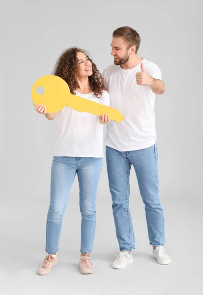 Glückliches Junges Paar Mit Großem Papierschlüssel Auf Grauem Hintergrund — Stockfoto