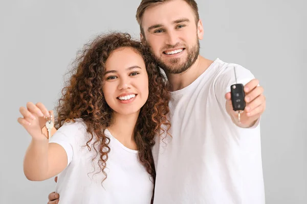 Pareja Joven Con Llave Coche Casa Sobre Fondo Gris — Foto de Stock