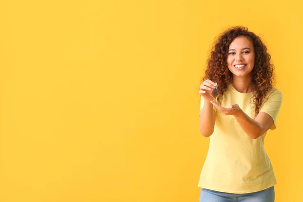 Happy young woman with key on color background