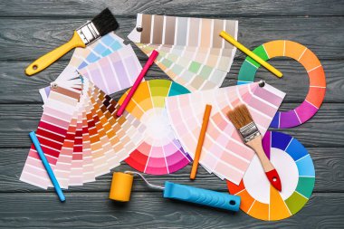 Tekerlekli paletler ve ahşap arka planda boya fırçaları