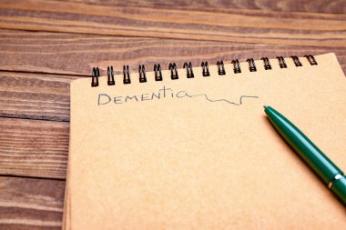 Tahta zemin üzerinde DEMENTIA ve kalem bulunan defter