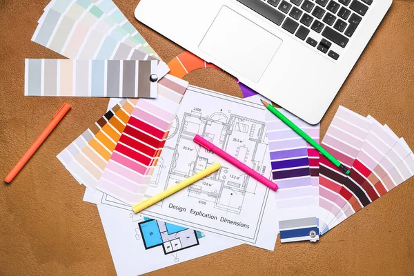 Color palettes with building plan and laptop on brown background