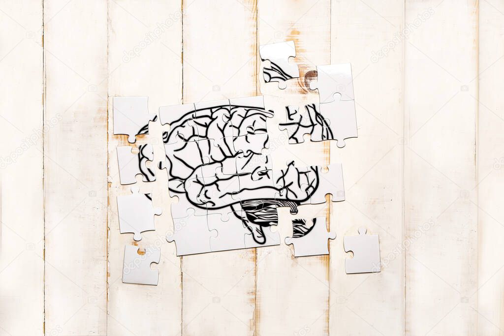 Puzzle with drawn human brain on white wooden background. Concept of dementia