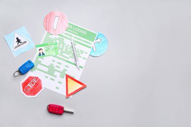 Gri arkaplanda başvuru formu, araba anahtarları ve yol işaretleri olan ehliyet