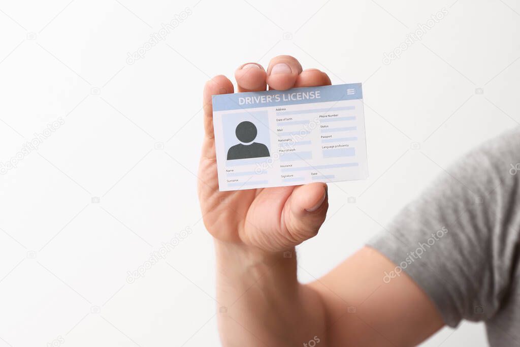 Male hand with driving license on white background