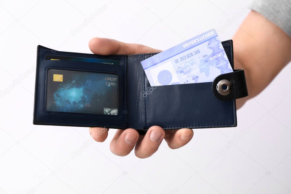 Male hand with driving license in wallet on white background