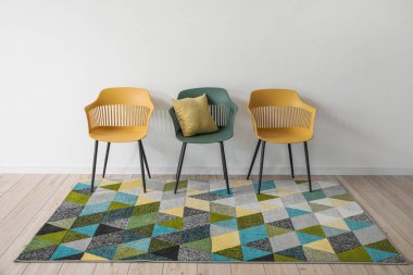 Oturma odasındaki hafif duvarın yanında yumuşak halılı şık sandalyeler.