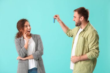 Renkli arka planda araba anahtarı olan genç bir çift