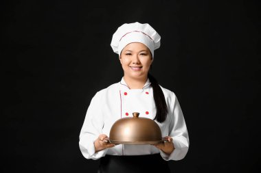 Koyu arkaplanda tepsisi olan güzel bir Asyalı şef.