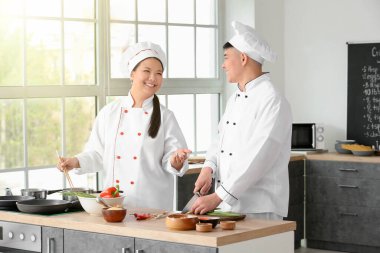 Asyalı aşçılar mutfakta birlikte yemek pişiriyor.