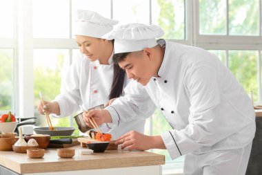 Asyalı aşçılar mutfakta birlikte yemek pişiriyor.