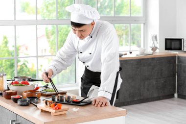 Yakışıklı Asyalı aşçı mutfakta yemek yapıyor.