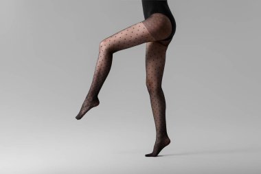 Gri arka planda tayt giymiş güzel bir kadın.