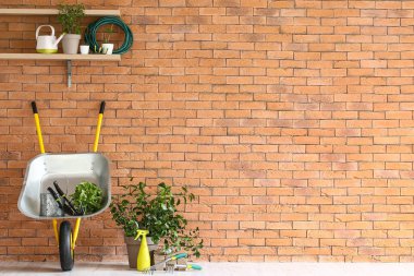 Tuğla duvarın yanında bahçe malzemeleri var.