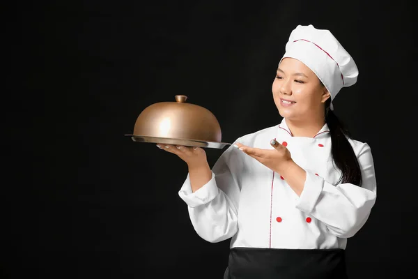 Beautiful Asian chef with tray on dark background