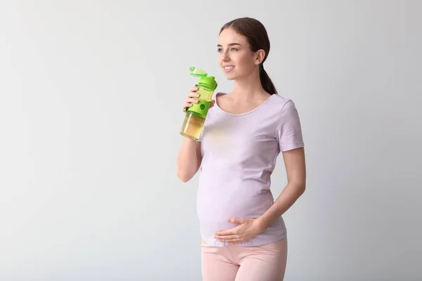 若いです妊娠中の女性のボトルの水の光の背景に — ストック写真