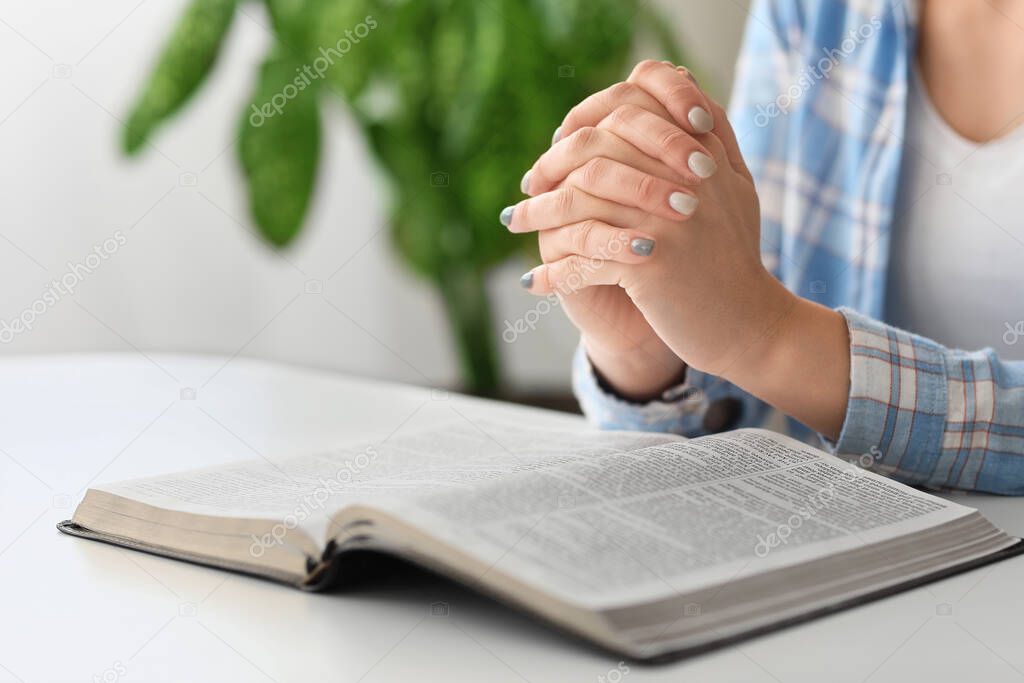 Young woman reading Bible at home, closeup