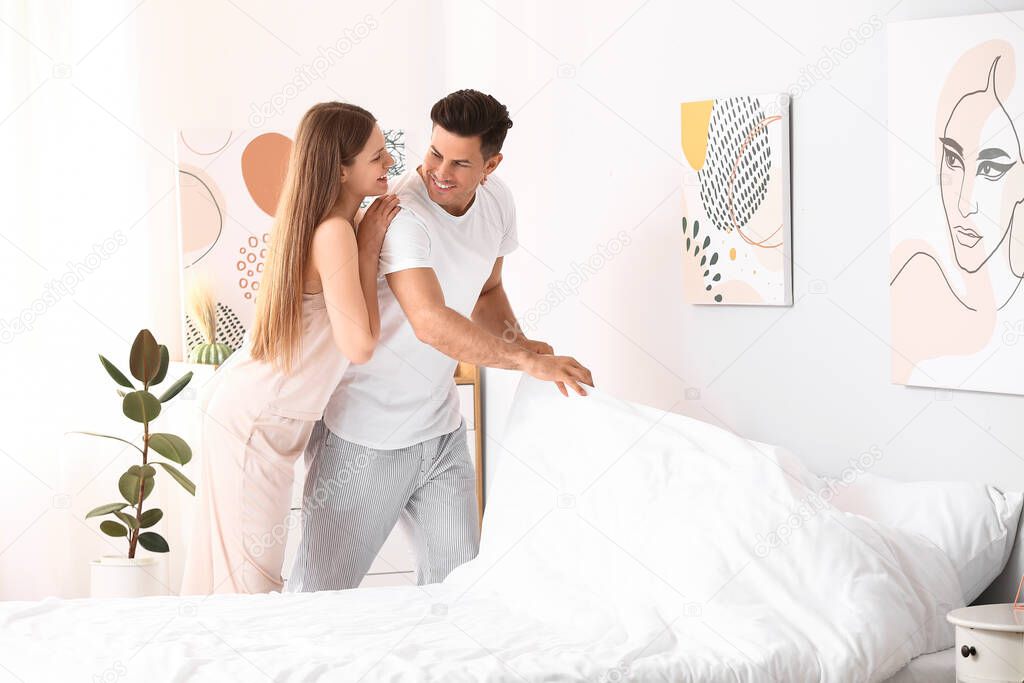 Morning of happy young couple changing bedclothes at home