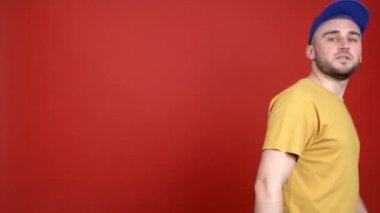 Genç adam ve kadın renkli arka planda şık şapkalar takıyor.