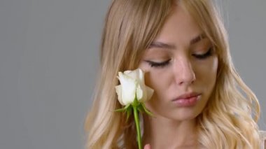 Gri arkaplanda beyaz gül olan güzel genç bir kadın.
