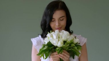 Arkaplanda beyaz güller olan güzel genç bir kadın.