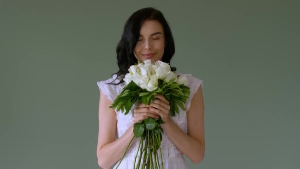 美丽的年轻女子带着一束色彩斑斓的白玫瑰向观众致意 — 图库视频影像