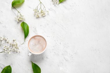 Beyaz arka planda çiçek dekoru olan bir fincan kahve.