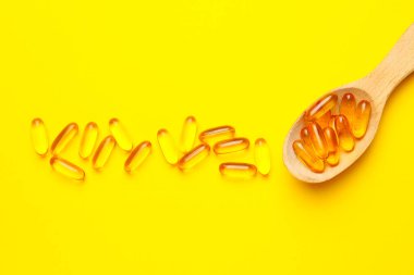 Renk arkaplanında balık yağı kapsüllü kaşık