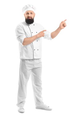 Yakışıklı erkek şef beyaz arka planda bir şeye işaret ediyor.