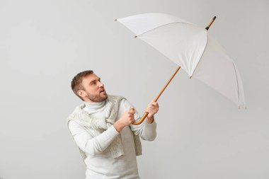 Hafif arka planda şemsiyesi olan yakışıklı bir genç.