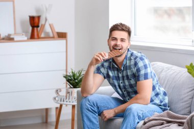 Evde lezzetli çikolataları olan yakışıklı bir genç.