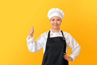 Güzel Asyalı şef, arka planda baş parmak hareketi gösteriyor