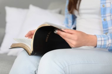 Evde İncil okuyan genç bir kadın, yakın çekim.