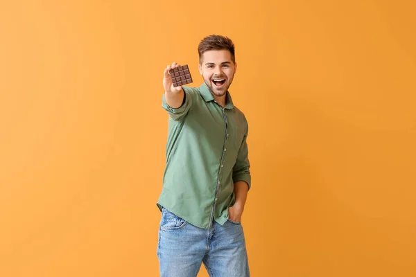 Schöner Junger Mann Mit Leckerer Schokolade Auf Farbigem Hintergrund — Stockfoto