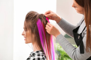 Kuaför, güzellik salonunda genç bir kadınla çalışıyor.