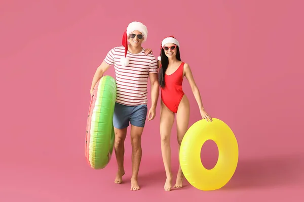 Young Couple Inflatable Rings Santa Hats Color Background — Stock Photo, Image