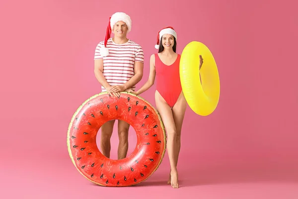 Young Couple Inflatable Rings Santa Hats Color Background — Stock Photo, Image