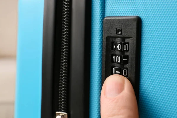 Man opening lock on suitcase, closeup