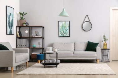 Şık koltuklar, masa ve raflar oturma odasının içinde.