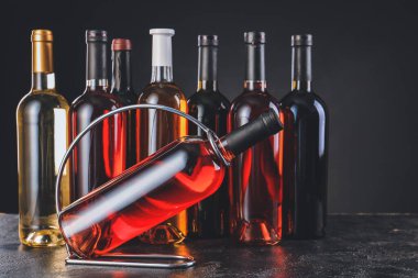 Siyah arka planda şarap şişeleri olan tutucu.