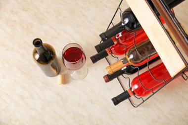 Elinde şişeler ve masada bir bardak şarap olan tutucu.